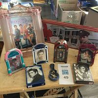 Overview of Elvis memorabilia including glass frame, jukeboxes, tins, VHS, trading cards