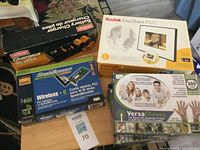 Group shot showing boxed Eveready charger, Kodak frame, Linksys adapter, and three Versa gloves boxes