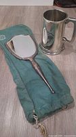 Birks sterling mirror on green pouch beside pewter tankard mug