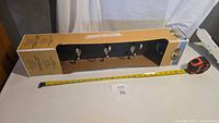 Boxed 5-hook coat rack on table with tape measure