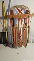 Front view of wooden sled showing painted slats, rope pull and measuring tape for scale