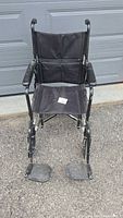 Front view of black folding wheelchair with footrests extended