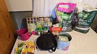 Overall view of lot showing soil bags, tray kit, watering can, bucket, kneeler, seeds and accessories