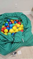 Green drawstring bag opened to show multicolor plastic balls inside