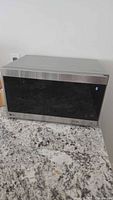 Front view of LG stainless steel microwave with black glass door and digital display