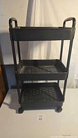 Front view of black 3-tier plastic rolling cart on casters