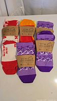 All five pairs of SneakySocks in original sleeves: three purple bicycle design, one orange, one red/white text