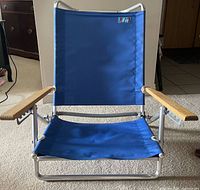 Front view of unfolded blue aluminum beach chair with wood armrests
