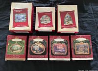 Front view of all seven Thomas Kinkade Hallmark ornament boxes