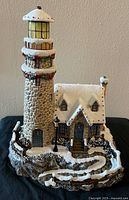 Front view of snow-covered lighthouse and cottage sculpture