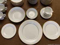 Overhead view showing assortment of plates, bowls, cup and saucer with gold rim