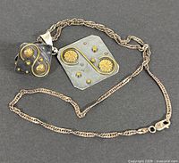 Sterling silver necklace with pendant and matching ring placed together showing design and size comparison.