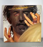 Front cover of Frank Zappa Joe's Garage Acts II & III double vinyl records showing the album art with Frank Zappa's face painted black and hands with rings.