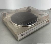 Side-angle photo of Dual CS 616Q turntable with closed dust cover visible with minor scratches and beige housing