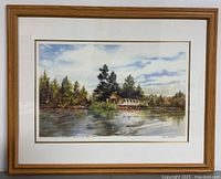 Full view of framed limited edition print showing wooded lake scene with cabin, wood frame and double matting.