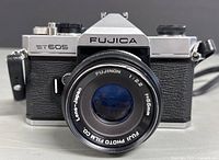 Front view shows Fujica ST605 with Fujinon 55mm f2.2 lens lens text clearly visible, camera in good condition with attached strap bowls.