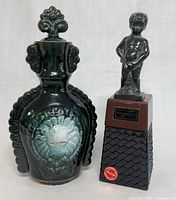 Photo showing the battery operated liquor dispenser with statuette and the vintage ceramic decanter side by side.