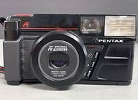 Front view of the black Pentax AF Zoom film camera showing the lens, built-in flash, and control buttons.