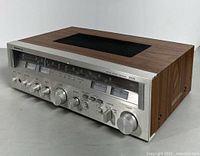 Front angle view of Sanyo 2033 AM/FM stereo receiver showing wood grain side panels and multiple control knobs on silver metal front panel.