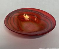 Top and angled view showing red and black coloration and glossy finish of the art glass bowl.