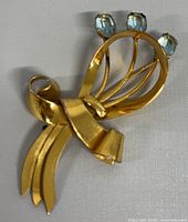 Front view of gold vermeil floral brooch with blue gemstone accents.