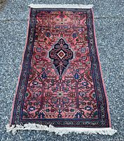 Full view of the antique Persian Heriz rug showing the central medallion and floral geometric pattern on salmon-pink field with navy border and fringes.