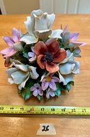 Top view of ceramic floral arrangement showing detailed pastel-colored flowers including white roses, red poppy, purple daisies, and green leaves with a measuring tape showing approximately 6.5 inches in diameter.