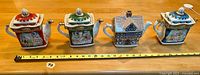 Four collector Sadler ceramic teapots lined up with measuring tape showing size approx 7-8 inches tall.