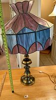 Full view of the handcrafted stained glass lamp showing the brass base and colorful stained glass shade with geometric patterns and arched panels.