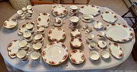 Full display of all bone china pieces on table showing plates, cups, bowls, and serving pieces.
