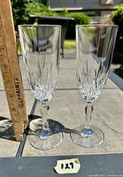 Pair of cut crystal champagne flutes standing outdoors with ruler showing height about 7 inches