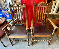 Pair of vintage wooden armchairs, showing turned legs, spindle backs, and leatherette upholstered seats in brown.