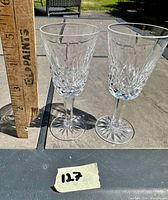 Two Waterford Lismore water goblets side by side with ruler for scale, outdoors on stone table showing approximate height of 6 7/8 inches.
