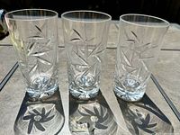 Three cut crystal tumblers in a row showing detailed starburst and fan cut patterns with clear reflections on a surface.