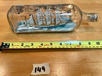 Photo of the vintage ship-in-a-bottle with measuring tape indicating approximate 8-inch length