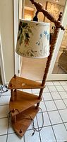 Full view of vintage corner floor lamp with two shelves and floral fabric shade, showing wood finish, lamp design and details.