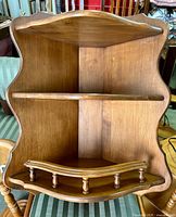 Full front view of vintage corner wall shelf showing three shelves and curved decorative edges