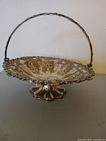 Full view of footed silver presentation basket with swing handle upright