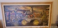 Full view of framed painting showing European townscape and bridge
