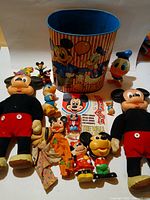 Group shot showing all fourteen Disney character items including dolls, figures, tin and booklet