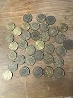 Group view of 34 Peruvian 10 Centimos coins spread on wooden surface