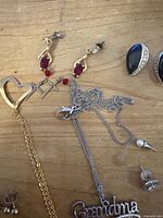 Overview of chains, pendants, red stone earrings, black cabochon earrings and various studs