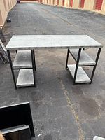 Full view of gray laminate desk with black metal legs and side shelves