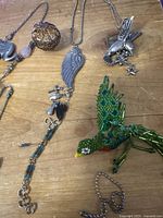 Overview showing multiple necklaces, parrot brooch, filigree ball pendant