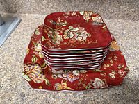 Stack showing large platter base and six small plates red floral square