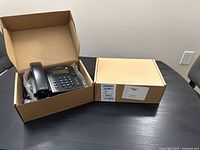 Two boxed Polycom VVX300 phones on table, one box open showing contents
