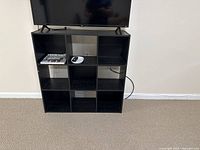 Front view of black 9-cube shelving unit under television