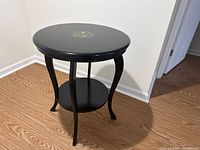 Full view of round black side table showing two tiers and curved legs
