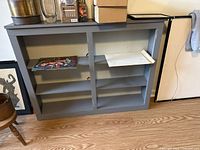 Front view of grey wooden shelf unit showing compartments and shelves