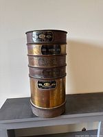 Stack of five brass testing sieves with bottom pan